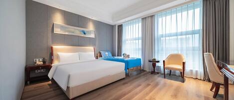 Una habitación de hotel con una cama grande, un escritorio, una silla y un televisor.