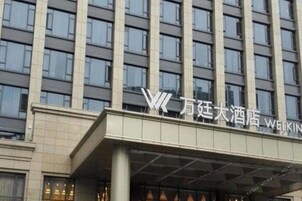 Un moderno edificio de hotel con una entrada destacada y un cartel grande que muestra el nombre del hotel.