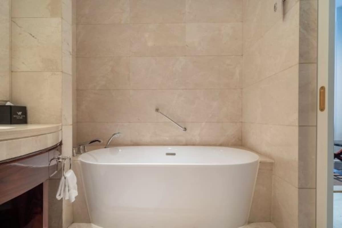 Une salle de bain moderne avec une baignoire sur pieds, un meuble-lavabo avec un miroir et une serviette accrochée au mur.