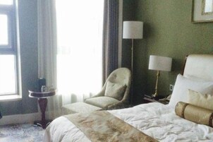 Una habitación de hotel con cama, una silla, una lámpara y una ventana.