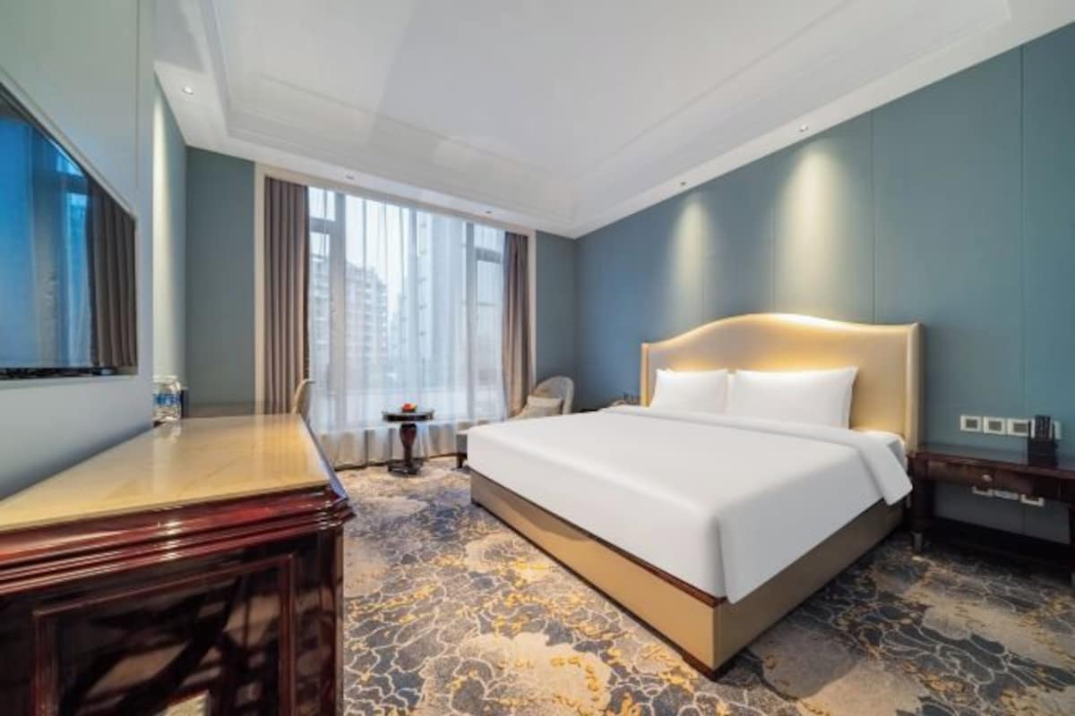 Une chambre d’hôtel avec un grand lit, un bureau, une chaise et une petite table.