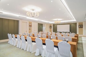 Un salón de conferencias con varias mesas y sillas, equipado con botellas de agua y tarjetas de identificación.