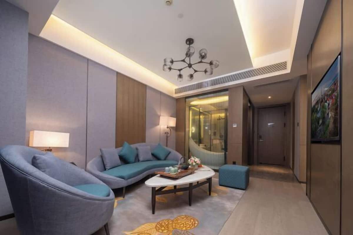 Un salon moderne avec un canapé, des fauteuils, une table basse et un lustre.