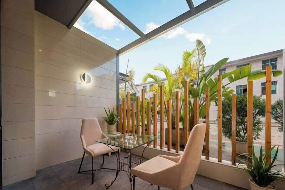 Un espace intérieur moderne, doté d’une table et de chaises en verre, entouré de cloisons en bambou et de plantes en pot.