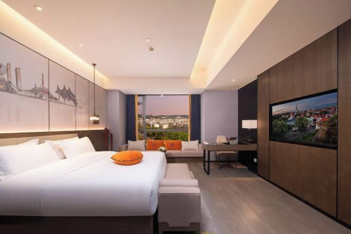 Une chambre d’hôtel moderne équipée d’un grand lit, d’un bureau, d’une chaise et d’un téléviseur.