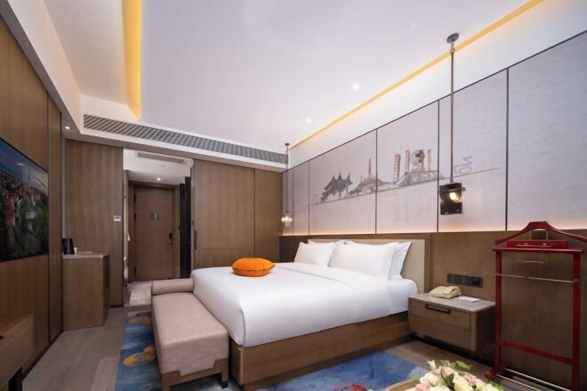 Una habitación de hotel moderna con una cama grande, mesitas de noche, un armario y un cuadro en la pared.