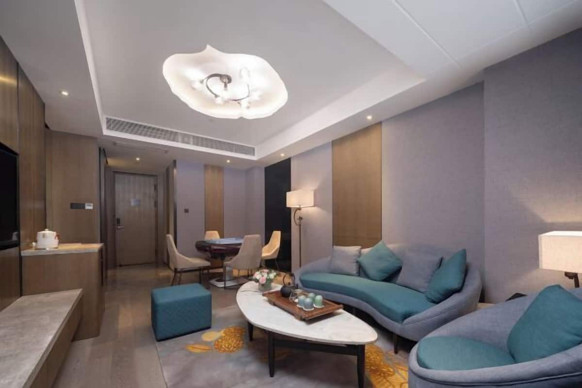 Une chambre d’hôtel moderne équipée d’un canapé, d’une table basse, d’un bureau et d’une télévision.