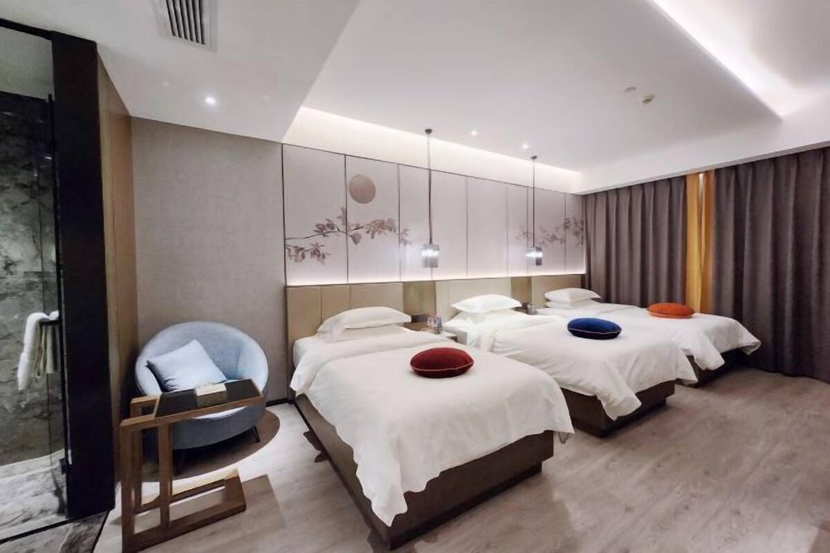 Une chambre d’hôtel moderne avec deux lits, un coin salon et un mur décoratif.