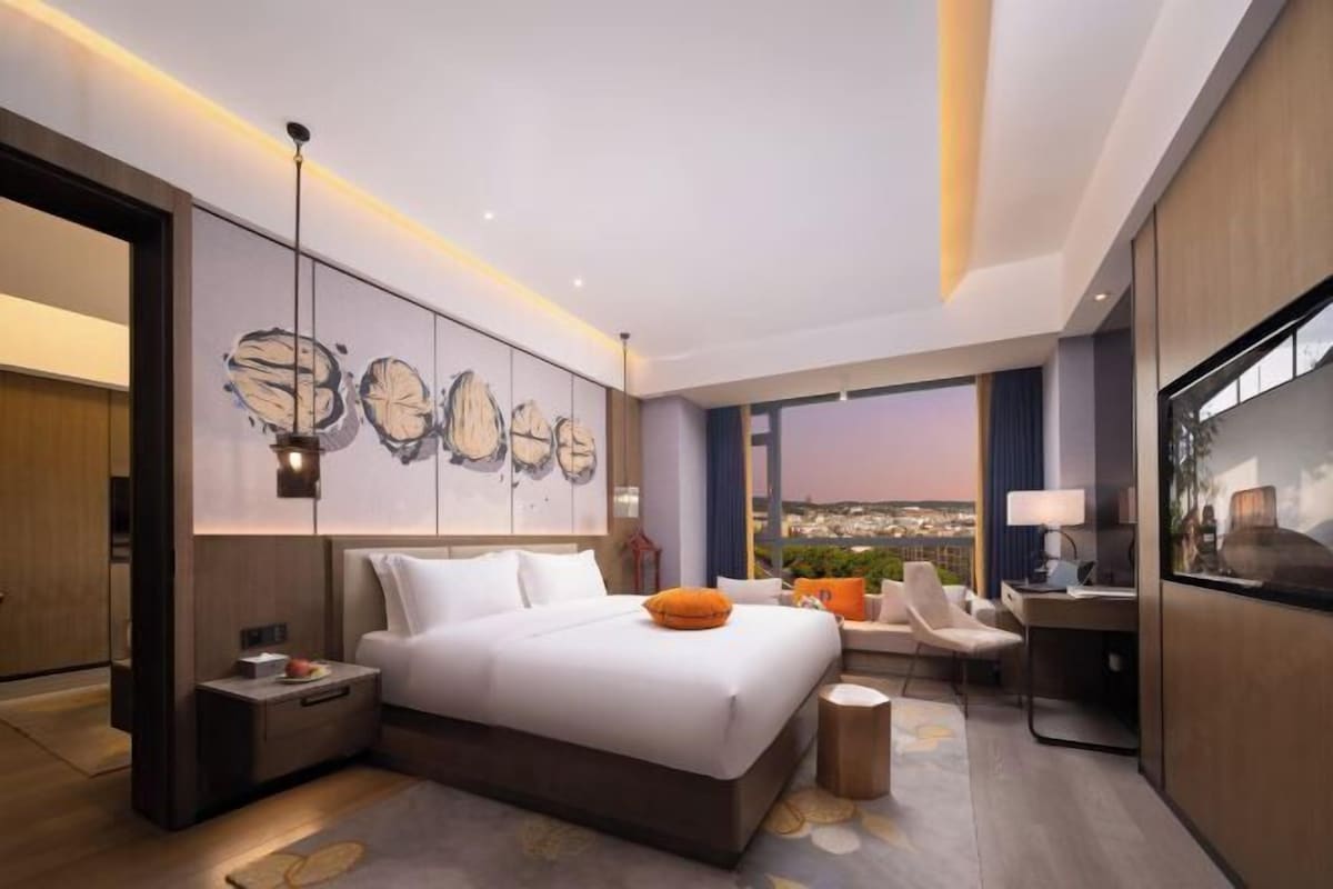 Habitación de hotel moderna con una cama grande, un escritorio y vistas a la ciudad.