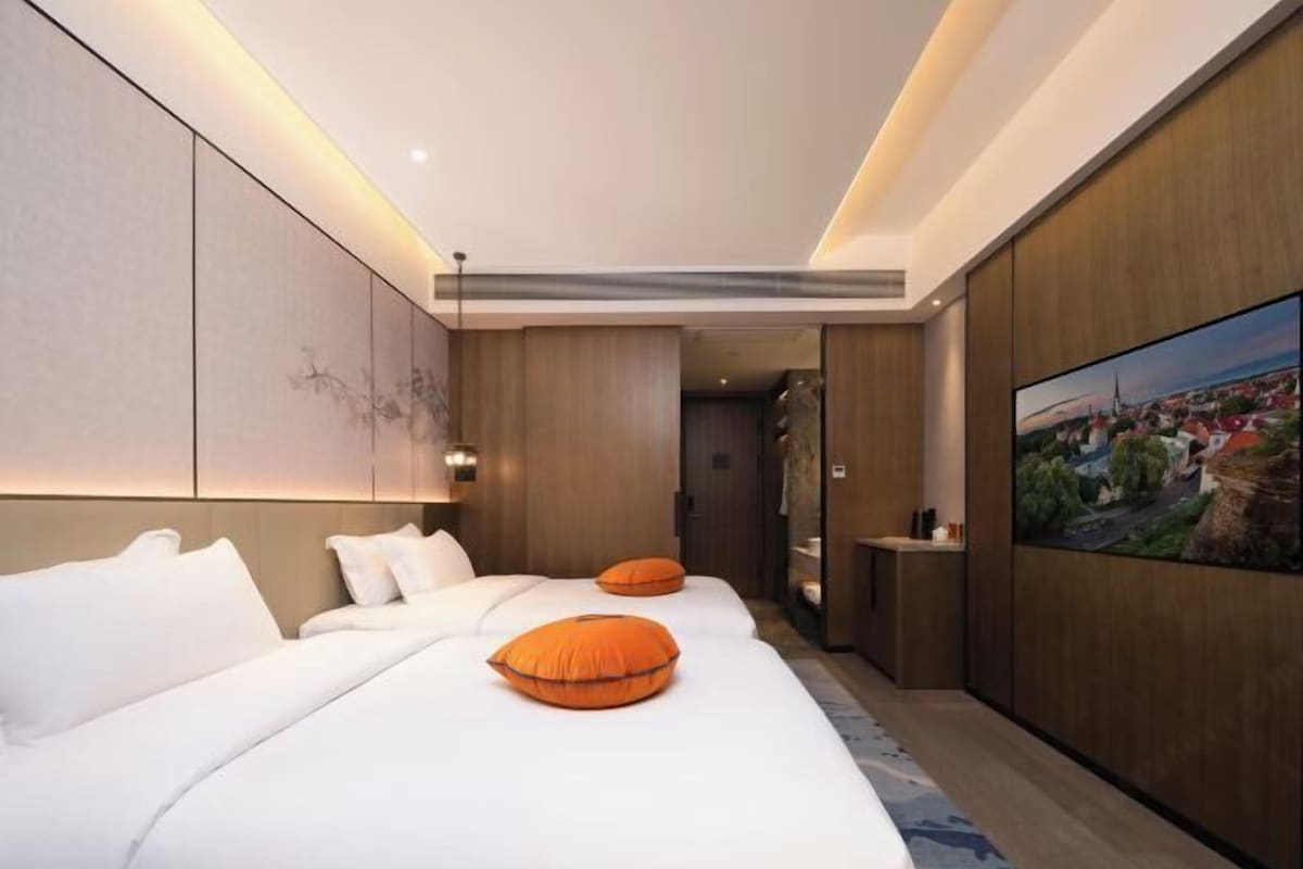 Una habitación de hotel con dos camas, un cuadro grande en la pared y una mesita.