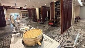 A buffet setup with a long counter, a large woven basket, and a variety of dishes. - Zhong Huang Hotel (Kunming)
