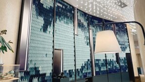 A modern interior with a large wall of blue and white tiles, a hanging light fixture, and a reception desk. - Zhong Huang Hotel (Kunming)