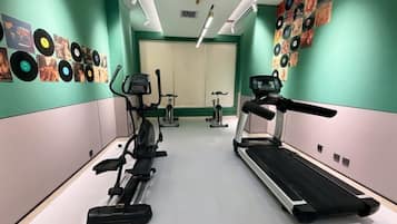 A gym with cardio machines, a treadmill, and wall decorations.