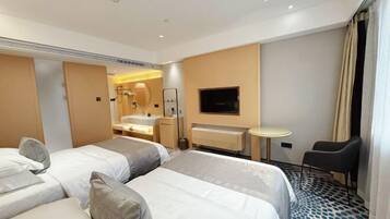Una habitación de hotel con dos camas, un televisor, una mesita y una silla.