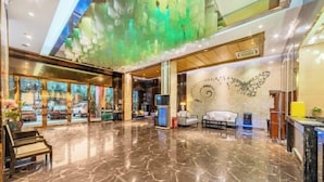 A spacious lobby with a marble floor, a reception desk, seating area, and a wall with a decorative design. - Sweet World Hotel (Foshan Jihuayuan, Zumiao) (Foshan)