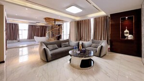 A modern living room with a sofa set, a round coffee table, and a staircase. - Sweet World Hotel (Foshan Jihuayuan, Zumiao) (Foshan)