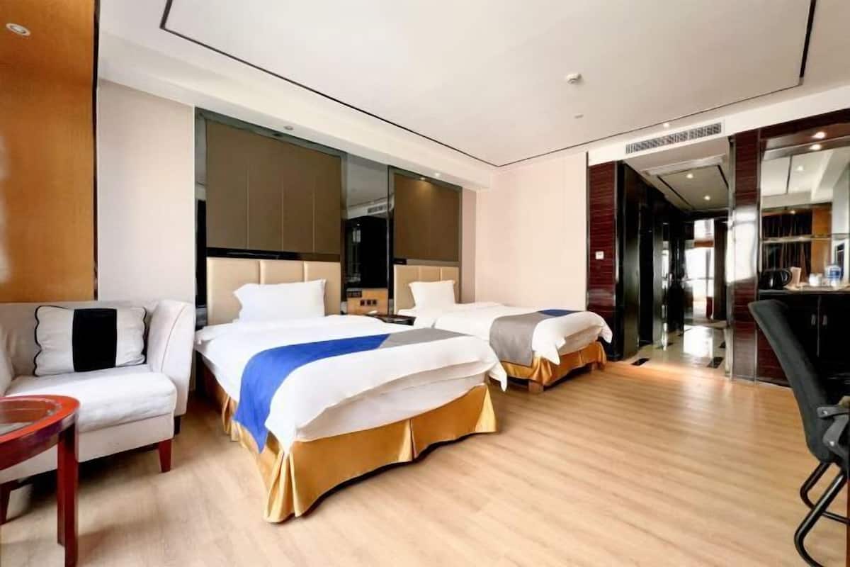 A hotel room with two beds, a sofa, a small table, and a mirror.