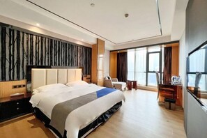A modern hotel room with a large bed, a desk, and a view of the city. - Sweet World Hotel (Foshan Jihuayuan, Zumiao) (Foshan)