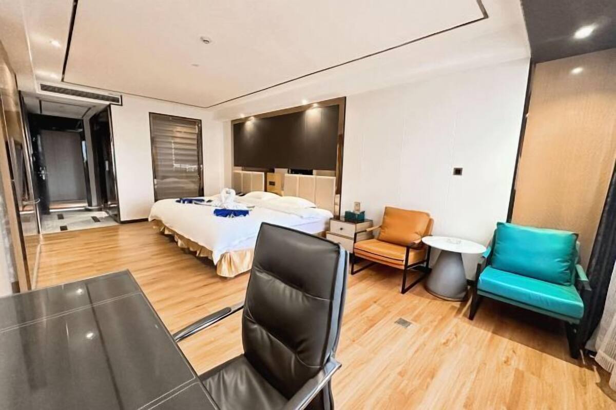 A hotel room with a bed, a desk, a chair, a small table, and a sofa.