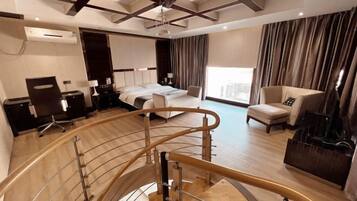 A modern hotel room with a curved staircase, a bed, a desk, and a seating area.