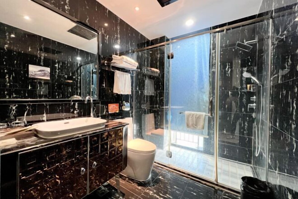 A modern bathroom with a large mirror, a sink, and a glass-enclosed shower area.