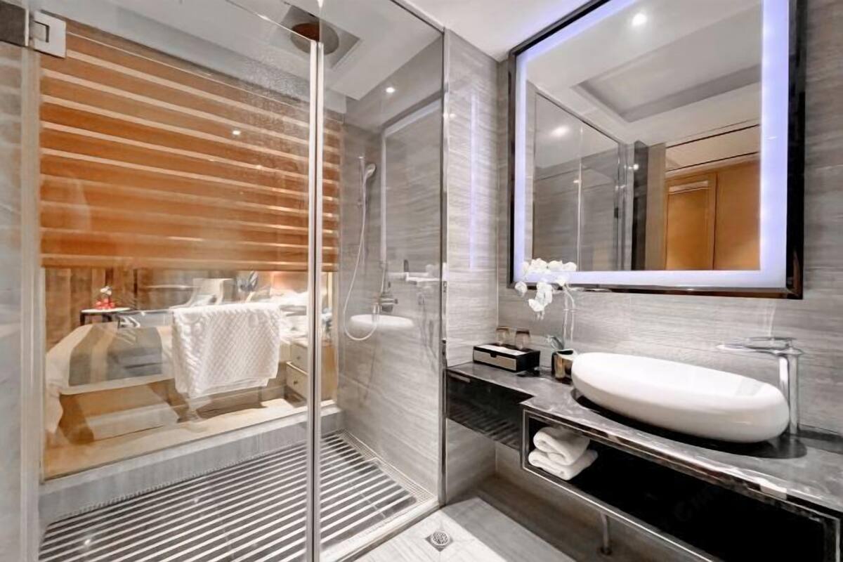 A modern bathroom with a glass shower enclosure, a large mirror, and a vanity with a sink.