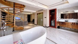 A modern bathroom with a freestanding bathtub, a wooden spiral staircase, and a vanity with multiple sinks. - Sweet World Hotel (Foshan Jihuayuan, Zumiao) (Foshan)