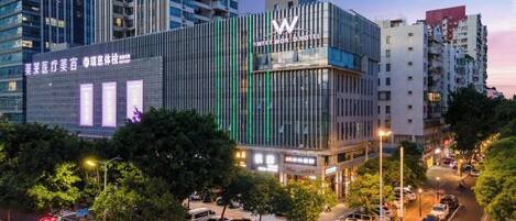 A modern hotel with a prominent 'W' logo, surrounded by urban buildings and a busy street.