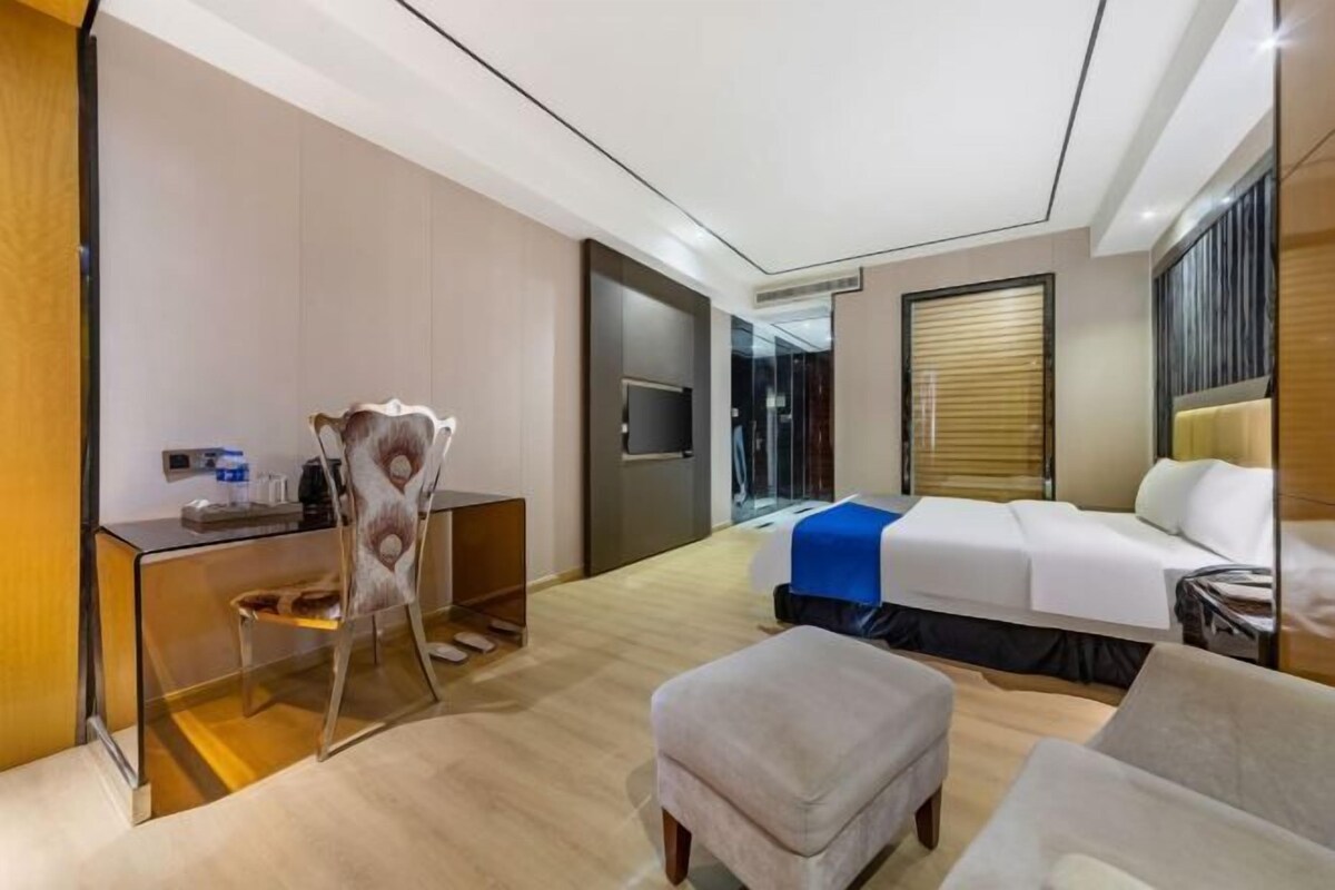 A modern hotel room with a bed, a desk, a chair, and a small table.