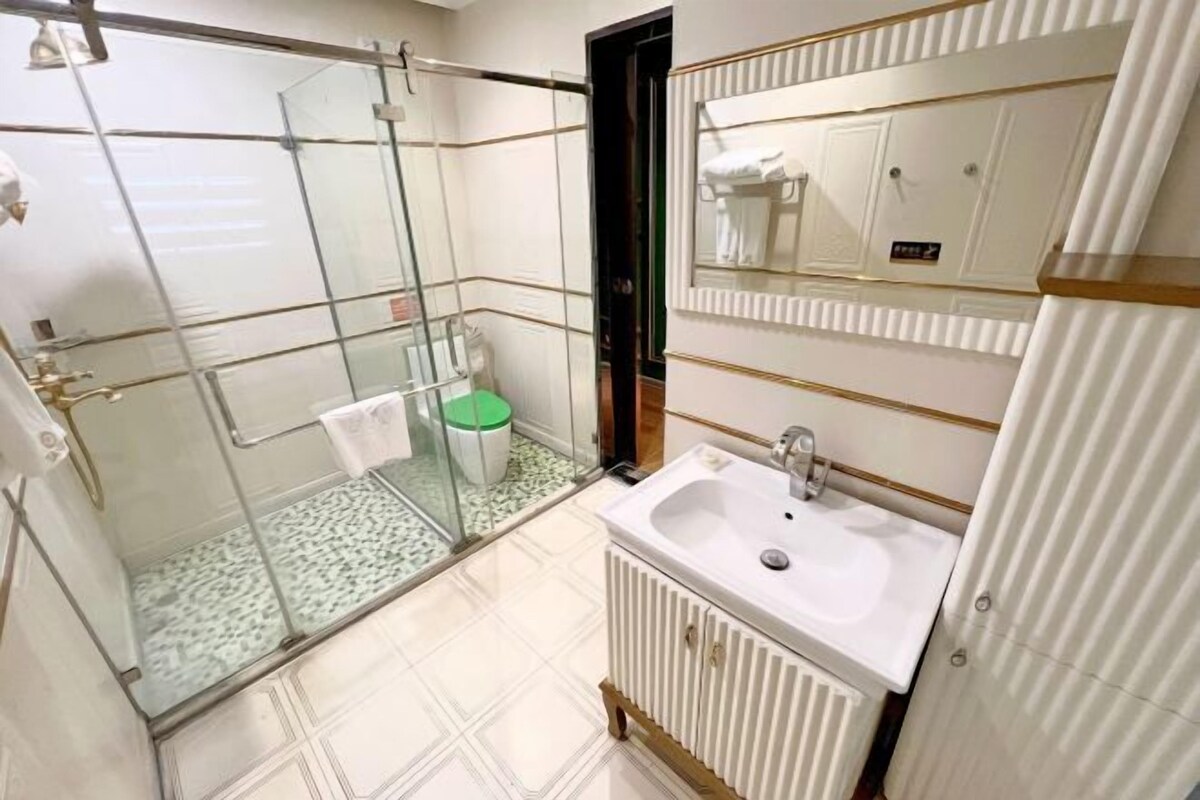 A bathroom with a glass shower enclosure, a sink, and a mirror.