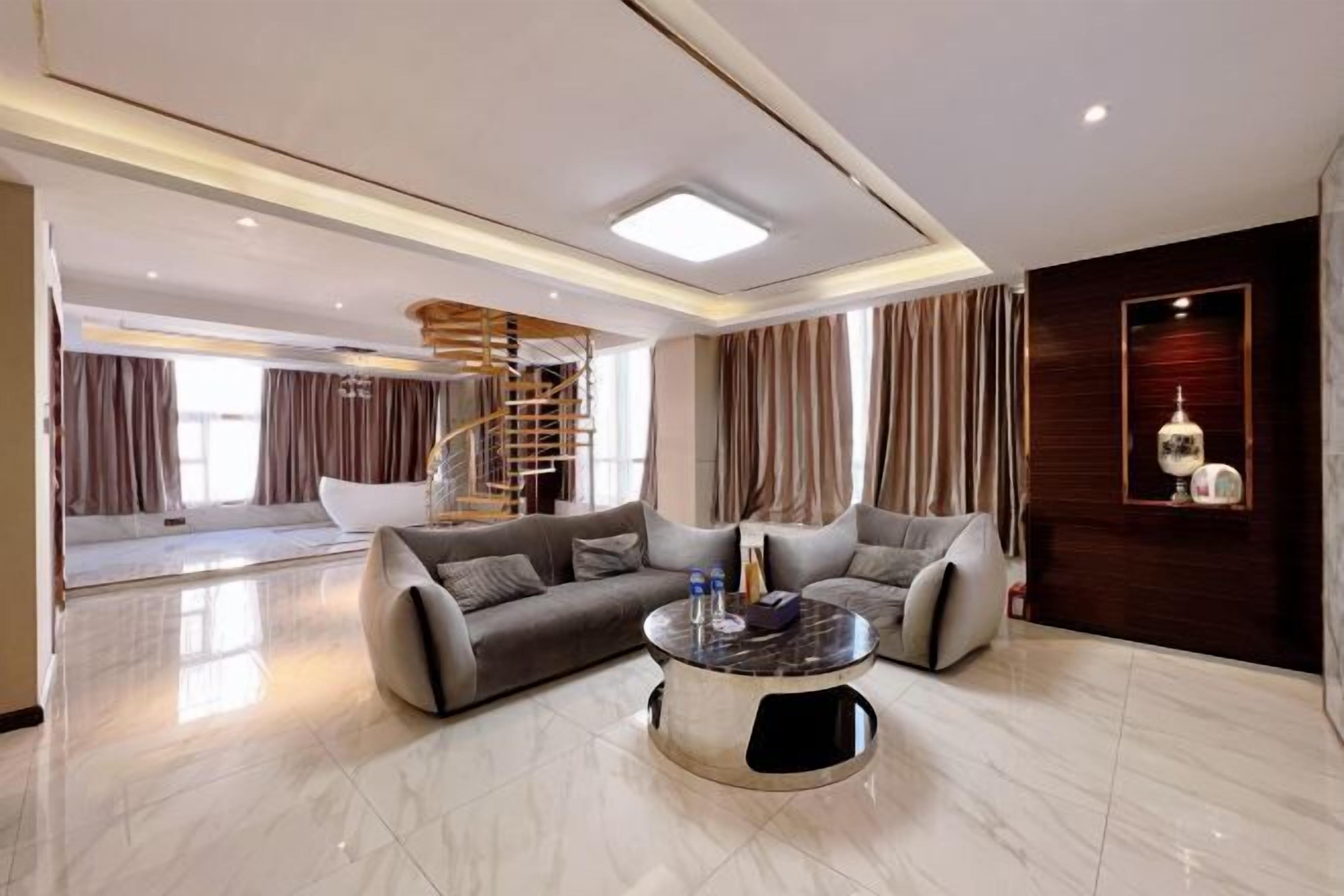 Uma sala de estar moderna com piso de mármore, dois sofás, uma mesa de centro e uma escada.
