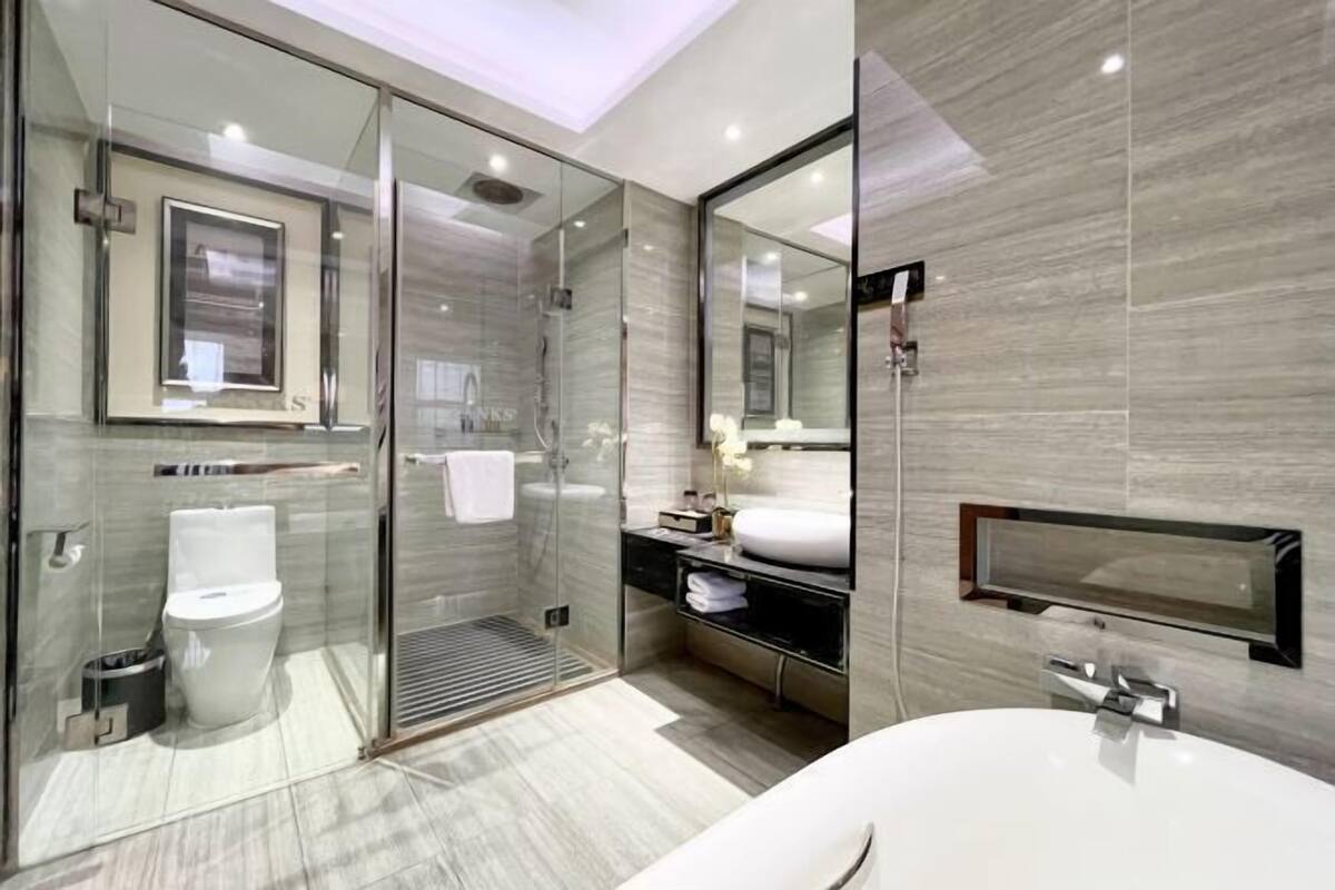 A modern bathroom with a glass-enclosed shower, a toilet, a sink, and a large mirror.