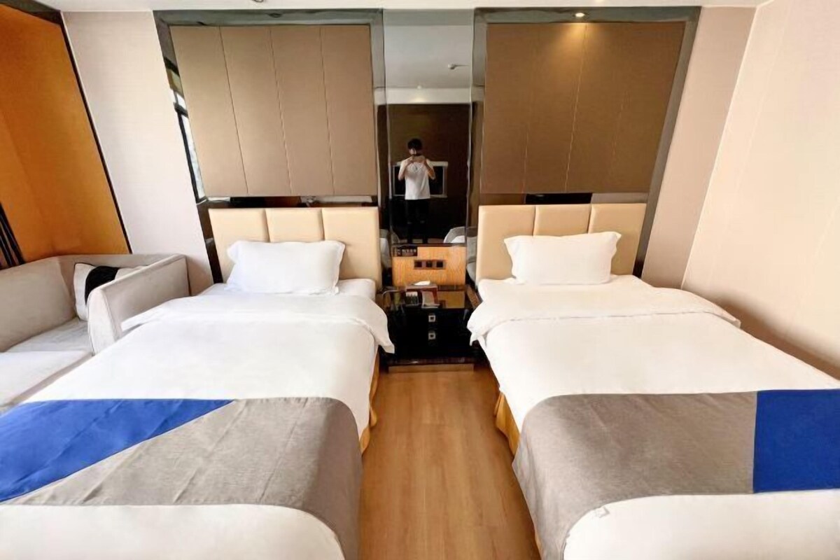 A hotel room with two beds, a small table, and a mirror.