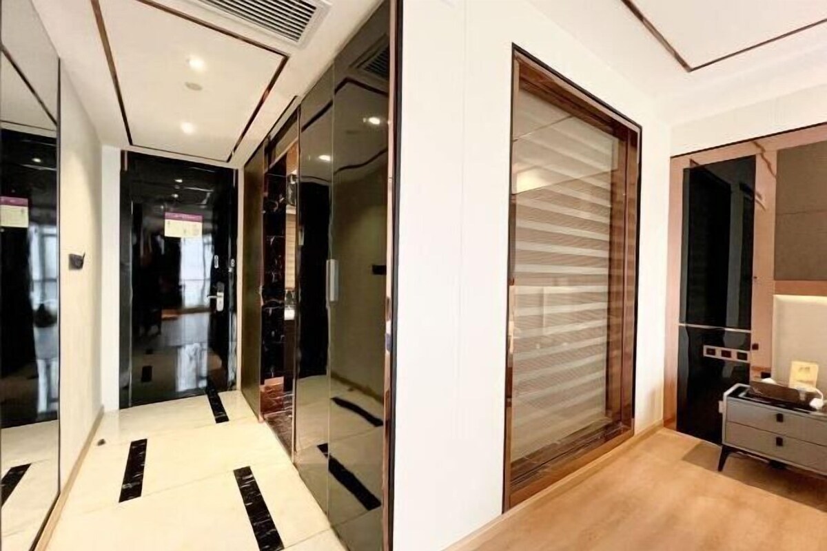 A modern hallway with glass doors leading to a room with a wooden floor and a large window.