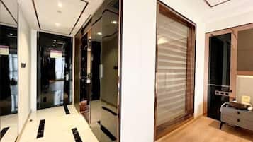 Um corredor moderno com portas de vidro que dão para um quarto com piso de madeira e uma grande janela.