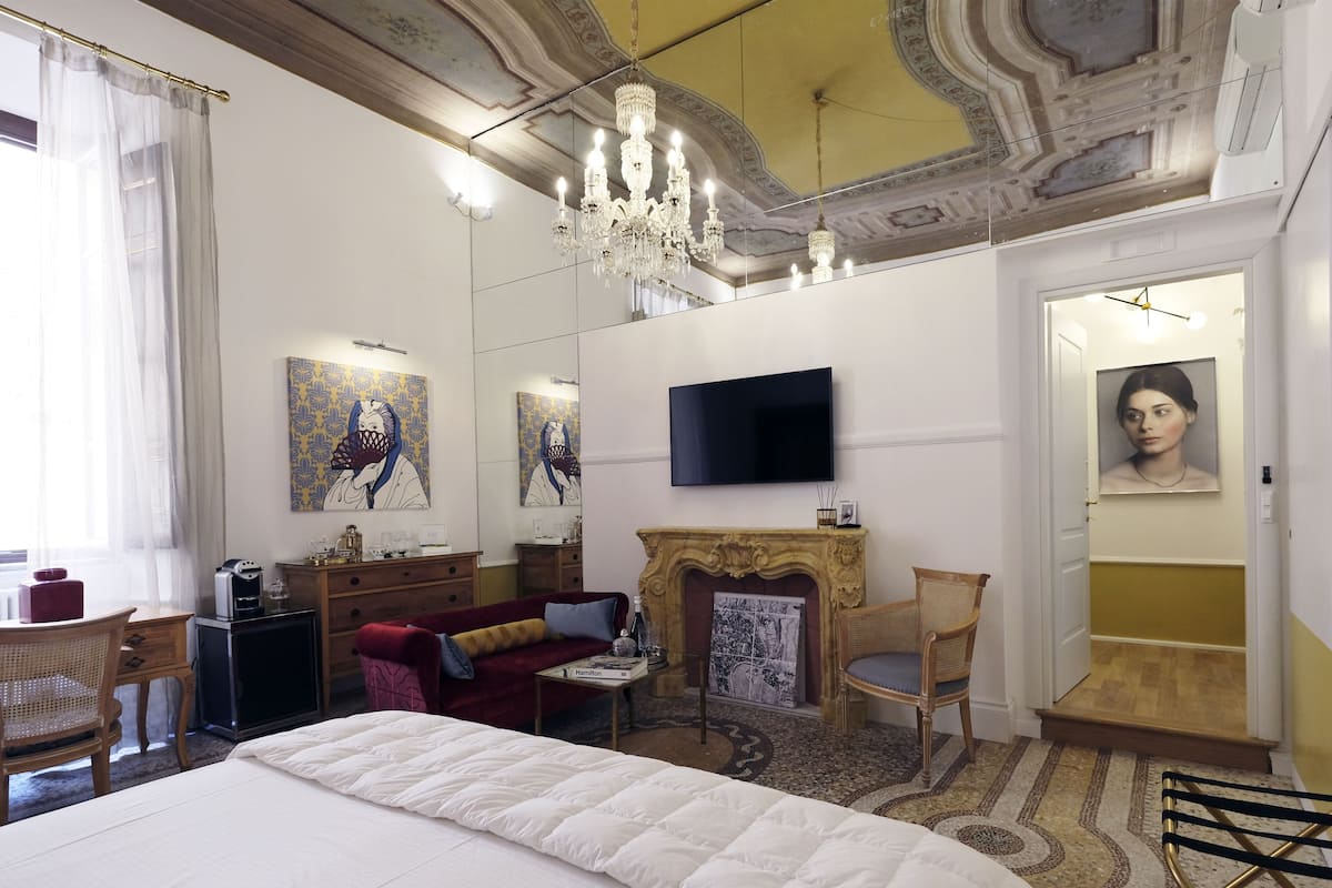 Un dormitorio espacioso con una cama grande, chimenea, televisor y obras de arte en las paredes.