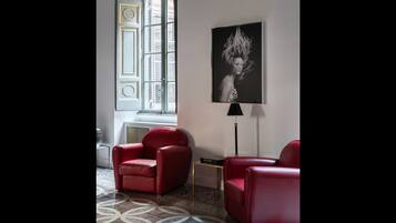 Una habitación moderna con dos sillones de cuero rojo, una lámpara de pie negra y una obra de arte en blanco y negro enmarcada en la pared.