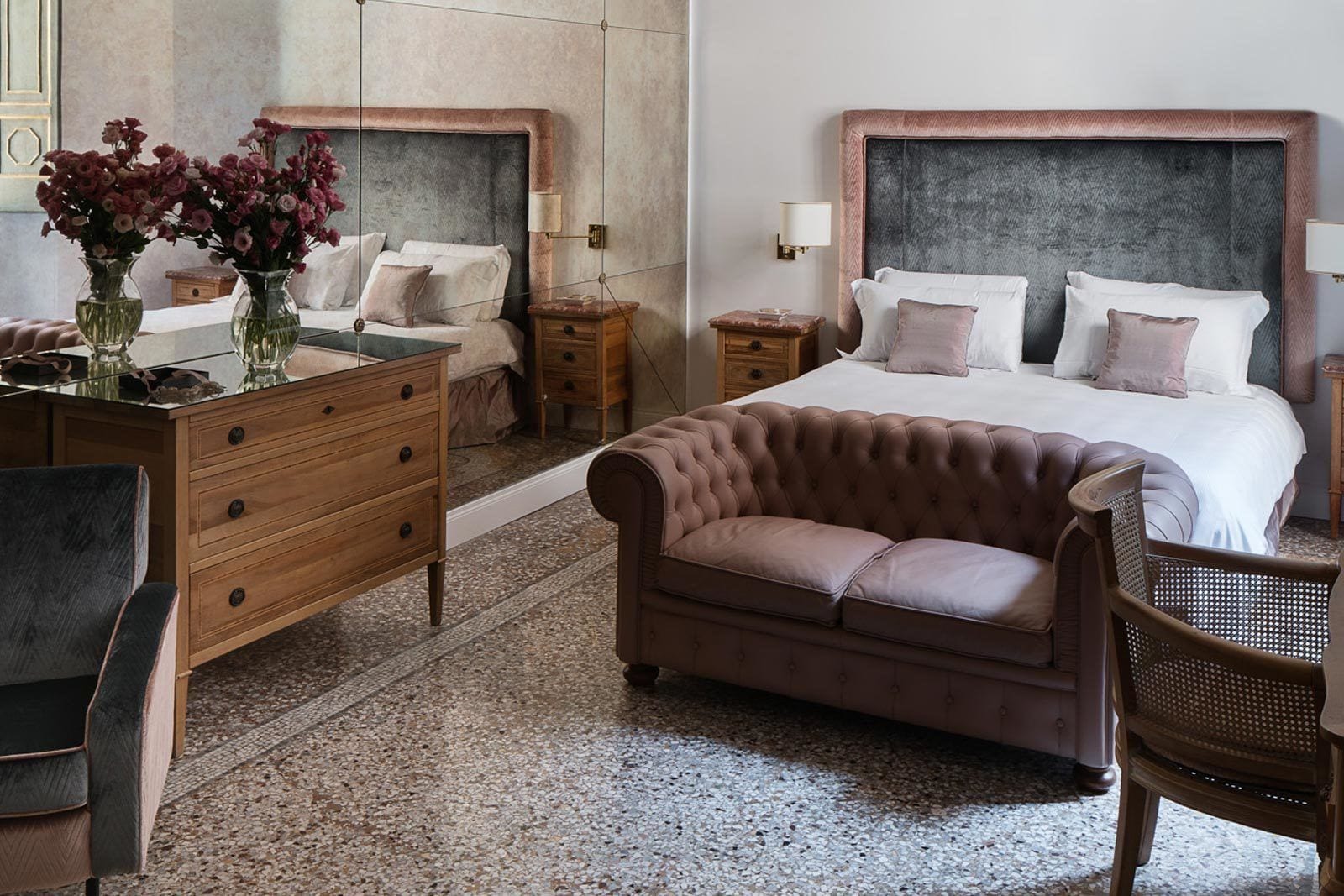 Ein Schlafzimmer mit einem großen Bett, zwei Nachttischen, einer Kommode, einer Chaiselongue und einem Sessel.