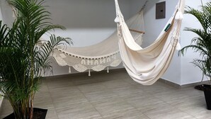 A hammock suspended from a wooden beam in a room with tiled flooring and white walls. - Las Perlitas Boutique Hotel (Sámara)
