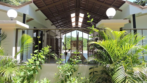 A covered outdoor area with a wooden roof, surrounded by lush greenery and a view of the landscape. - Las Perlitas Boutique Hotel (Sámara)