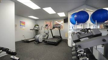 A gym with treadmills, elliptical machines, and free weights.