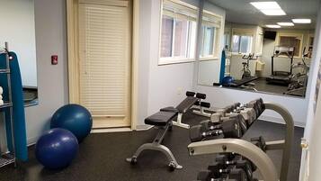 Ett gym med träningsredskap, en bänk och träningsbollar.