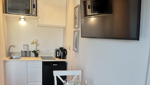 Cocina compacta equipada con microondas, tostadora y cafetera. Se observa una mesa de comedor dispuesta con platos, vasos y cubiertos.