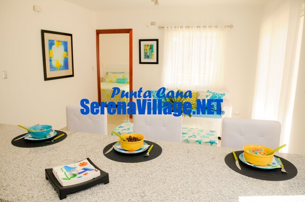 A dining area with a table set for breakfast, featuring bowls of cereal and a cake. - Serena Village (Punta Cana)
