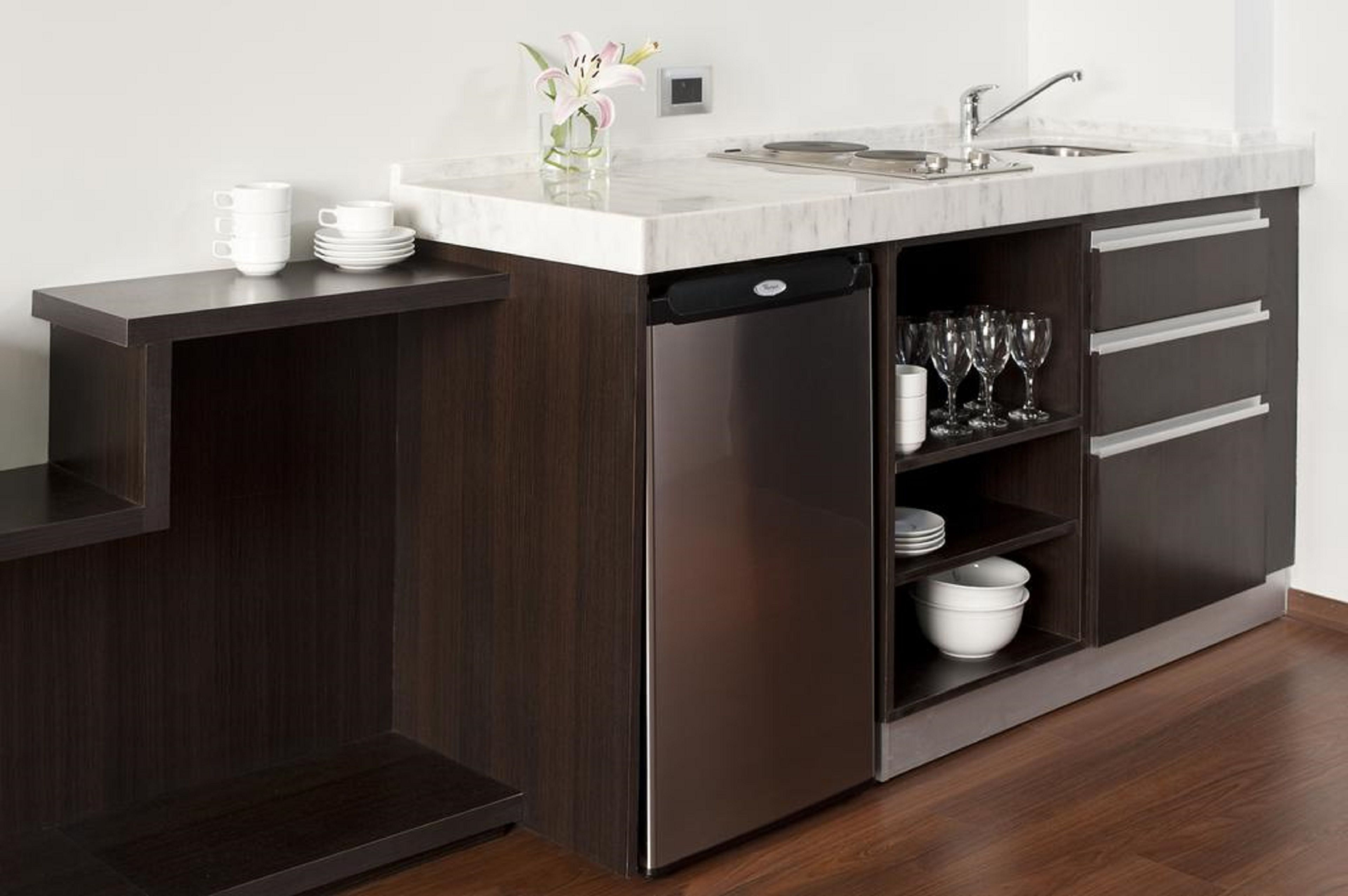 Una cocina moderna con lavavajillas integrado, encimera de mármol y un mueble de madera oscura con cajones y estantes.