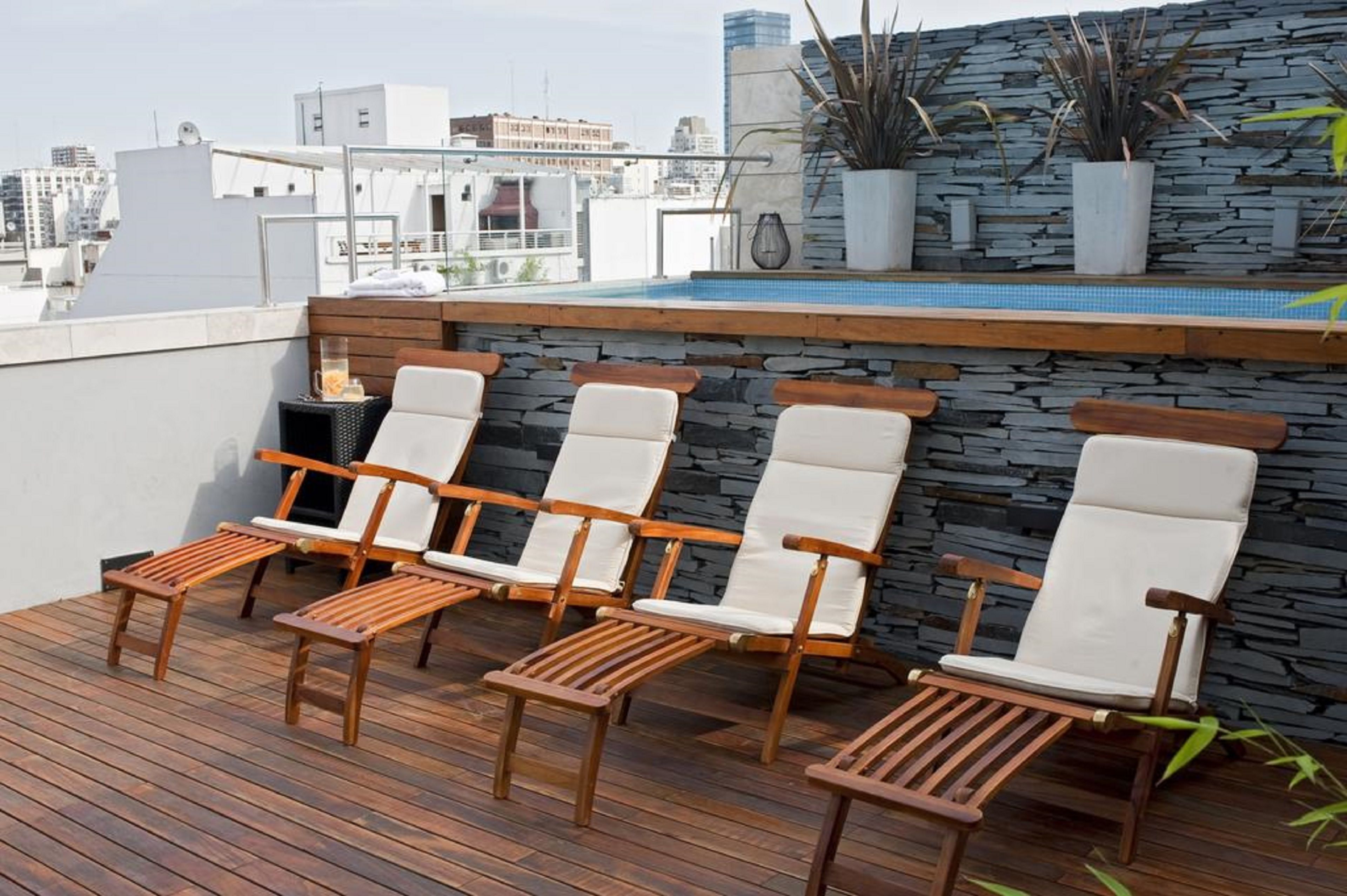 Une terrasse sur le toit, dotée de chaises longues en bois et d’un mur en pierre.