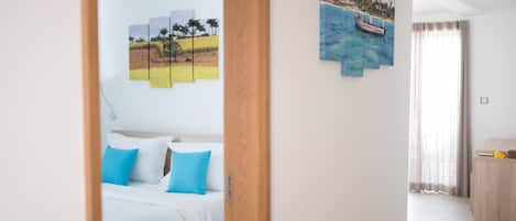 Una habitación de hotel con una cama, una puerta de madera y una pared con un cuadro de paisaje.