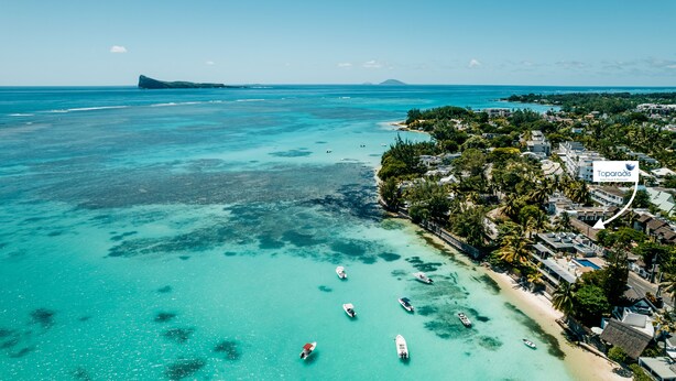 Vista aérea de una zona costera con aguas turquesas cristalinas, barcos y un hotel llamado Toparadis.