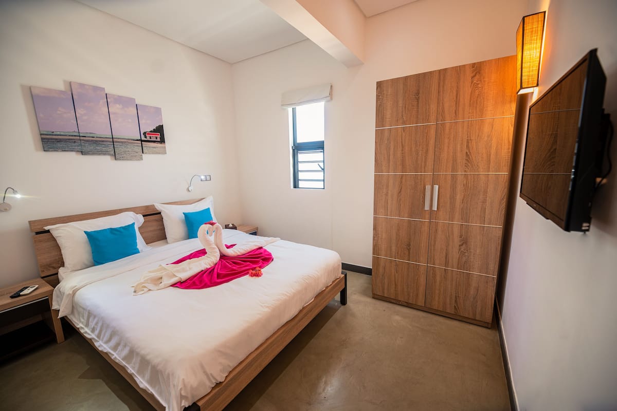 A hotel room with a bed, a wardrobe, a wall-mounted TV, and a window.