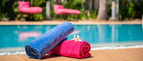 Ein Poolbereich mit Holzdeck, zwei zusammengerollten Handtüchern und einem Pool im Hintergrund.